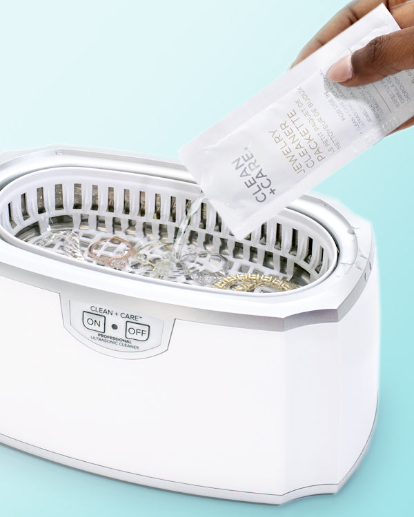 Jewelry Cleaner Packette being poured into an ultrasonic cleaner with jewelry 