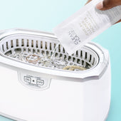 Jewelry Cleaner Packette being poured into an ultrasonic cleaner with jewelry 
