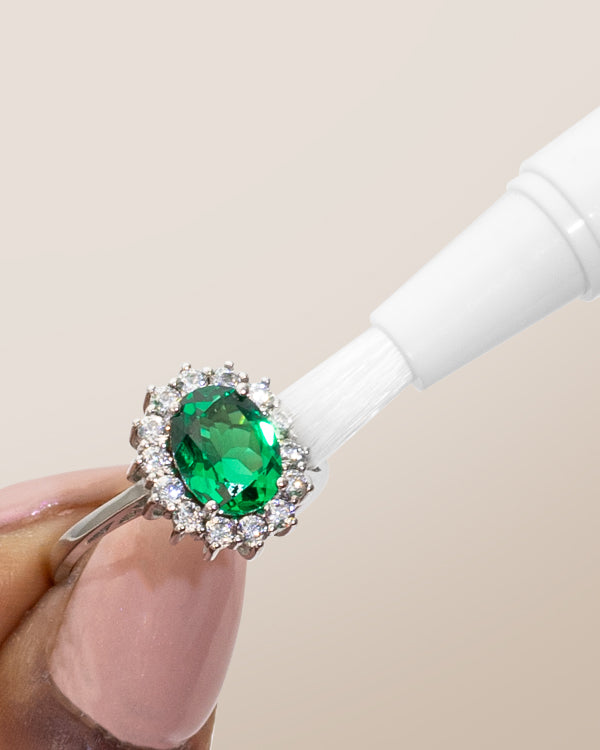 Clean + Care's Jewelry Cleaning Stick in use on an emerald and diamond ring