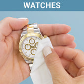 CLEAN+CARE Jewelry + Watch Cleansing Wipe in use on a gold and silver watch