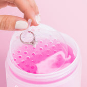 Hand dripping a diamond ring & jewelry dipping basket into a jar of Fine Jewelry Cleaner