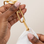 Clean + Care Jewelry Cleaning Wipe in use on a gold chain