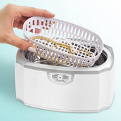 Hand dripping a basket full of jewelry into an Ultrasonic Cleaning Machine