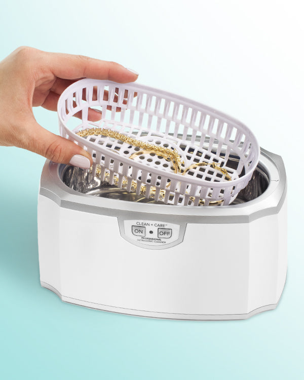 Hand dripping a basket full of jewelry into an Ultrasonic Cleaning Machine
